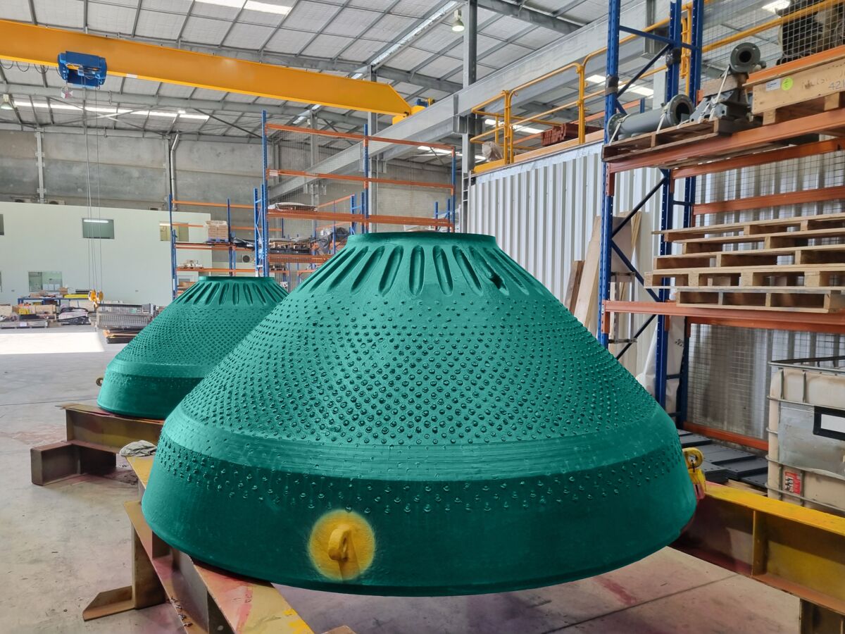 Metso Outotec experts next to crusher wear part
