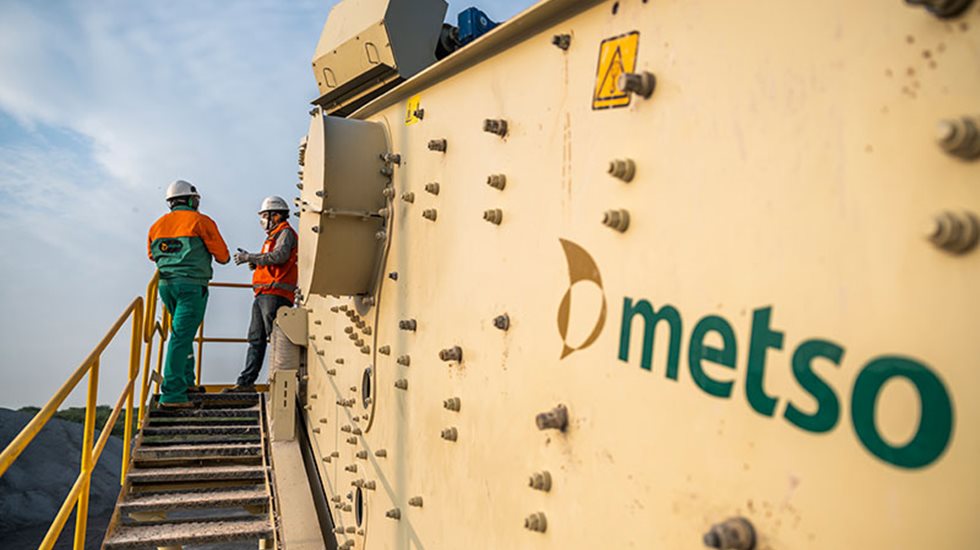 Two men talking with each other next to aggregate equipment.