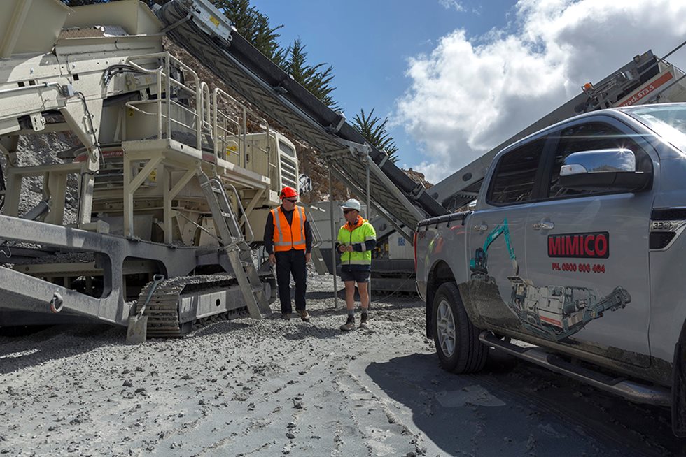 Two men at a quarry next to a mobile crusher.