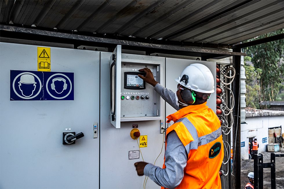 Man in front of control cabinet, handling the controls. 