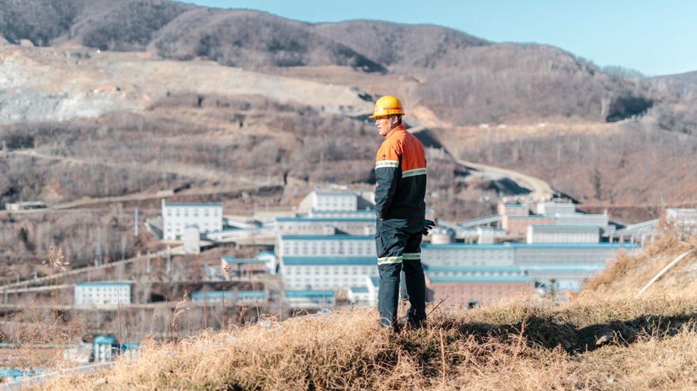 Man looking down from a small hill, down to the Hunchun Zijin mining site.